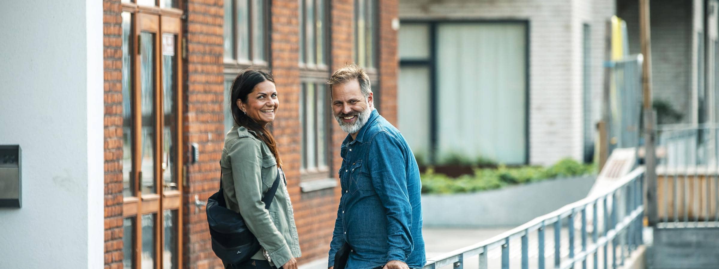 En mand og en kviden står ude foran en etageejendom