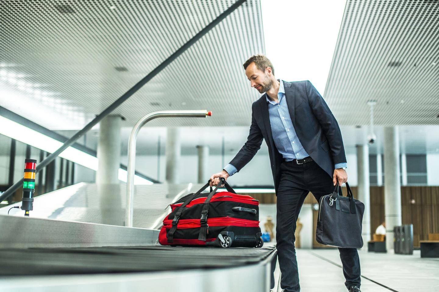 Mand, der tager sin rejsetaske fra et rullebånd i lufthavn